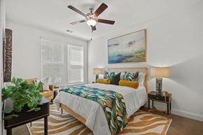 Wake Forest apartment for rent - A bedroom with a bed, a ceiling fan, and a painting on the wall.