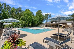 Wake Forest apartment for rent - A large swimming pool surrounded by lounge chairs and umbrellas.