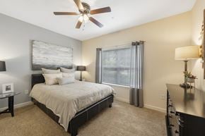 Macon apartment for rent - A bedroom with a bed, a ceiling fan, and a window with curtains.