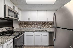 Savannah apartment for rent - A kitchen with a stainless steel refrigerator, black oven, and white cabinets.