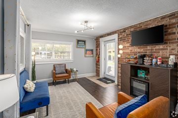 Savannah apartment for rent - A living room with a blue couch, a brown chair, and a television mounted on a brick wall.