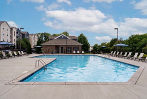 Knoxville apartment for rent - A large outdoor swimming pool with lounge chairs and a building in the background.