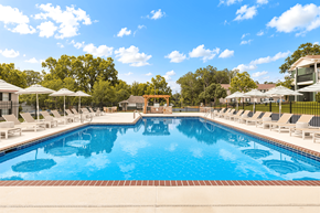 Tuscaloosa apartment for rent - A large swimming pool surrounded by lounge chairs and umbrellas.