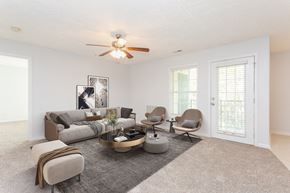 Fayetteville apartment for rent - A living room with a grey sofa, a grey armchair, a grey ottoman, a coffee table, and a ceiling fan.