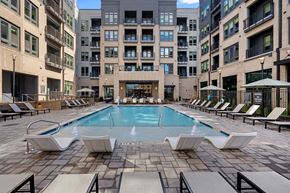 Cary apartment for rent - A large swimming pool surrounded by lounge chairs in a courtyard.