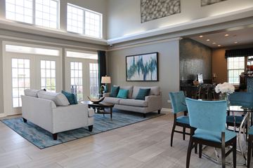 Waukegan apartment for rent - A living room with a white couch, blue chairs, and a painting on the wall.