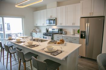 A kitchen with a large island and a stainless steel refrigerator