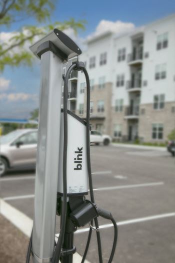 A gas pump in a parking lot in front of an apartment building
