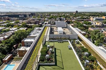 An aerial view of a rooftop garden with a pool and a city in the background