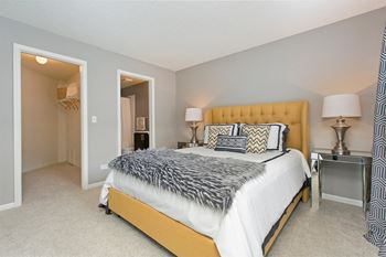A bedroom with a large bed and a nightstand with lamps