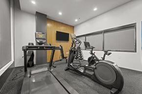 Deerfield apartment for rent - A treadmill and a stationary bike are in a room with a wooden panel wall.