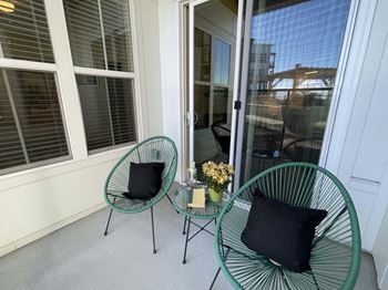 Two green chairs with black pillows are on a patio