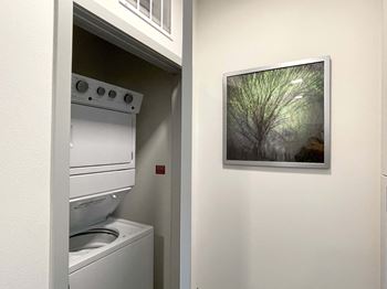 A picture of a tree is hanging on the wall next to a washing machine