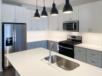 A kitchen with white counter top and stainless steel appliances