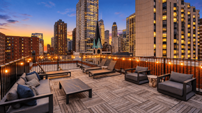 Chicago apartment for rent - A rooftop patio with a table and chairs overlooking a city skyline at dusk.