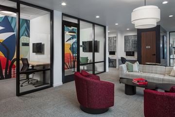 Wauwatosa apartment for rent - A modern living room with a grey sofa, a red chair and a glass wall.