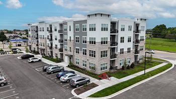 An aerial view of an apartment building with cars parked in a parking lot