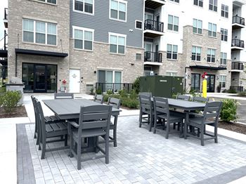 A patio with a table and chairs in front of an apartment building