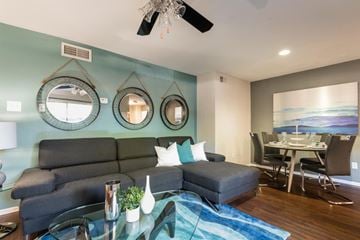 Fort Worth apartment for rent - A living room with a grey sofa, a glass coffee table, and a dining table with chairs.