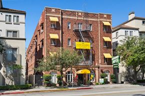 Pasadena apartment for rent - A red brick building with a yellow awning and a sign that says Now Leasing at Brookmore Pasadena apartments.