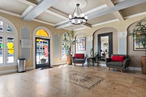 Pasadena apartment for rent - A spacious lobby with a chandelier, sofas, and a large rug at the Brookmore Apartments leasing office.
