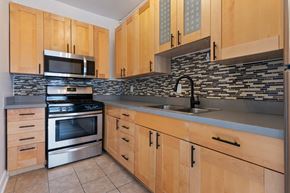 Pasadena apartment for rent - A kitchen with wooden cabinets and a stone backsplash at Brookmore Apartments Pasadena, CA