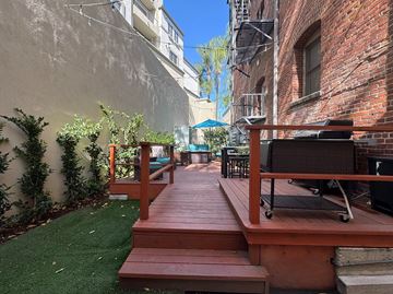 Pasadena apartment for rent - A wooden deck with a table and chairs is surrounded by greenery.