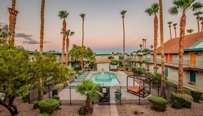 Las Vegas apartment for rent - A pool surrounded by palm trees and a fence.