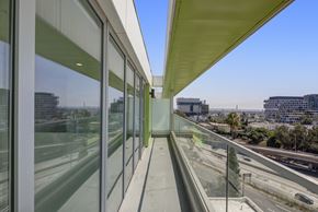 Los Angeles apartment for rent - Fusion Hollywood private balcony with glass windows on the side and a view of the highway and buildings outside.