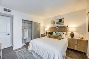 Woodland Hills apartment for rent - Fusion Warner Center Woodland Hills apartment. One bedroom apartment in Woodland Hills CA carpeted bedroom with frosted glass doors on closet and large bed with white boho duvet.