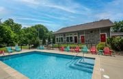 Hendersonville apartment for rent - Retreat at Indian Lake Apartments Hendersonville TN swimming pool with red chairs and a building in the background.