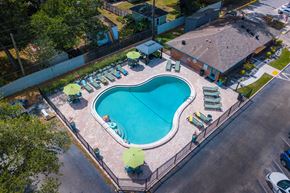 Lakeland apartment for rent - Aerial view of community pool at Watermarc luxury Apartments in Lakeland, FL with large pool house and green lounge chairs with green umbrellas