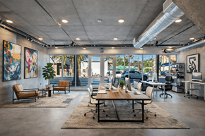 Los Angeles apartment for rent - A modern office space with a large table and chairs in the foreground and a view of the outside through the windows at Fusion Hollywood.
