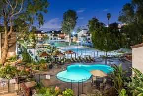 Woodland Hills apartment for rent - Fusion Warner Center luxury apartments in Woodland Hills pool, courtyard, and tennis courts lit at night and surrounded by palm trees.