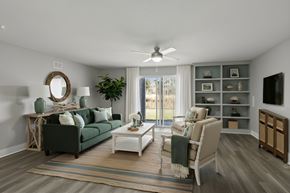 Jacksonville apartment for rent - A living room with a green couch, a white coffee table, and a large window with a view of the outside at Mandarin Bay Apartments.