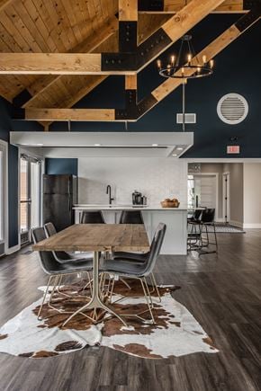 Westerville apartment for rent - Fairway Lakes gathering area featuring a table surrounded by five chairs and hardwood-style flooring, next to a communal kitchen.