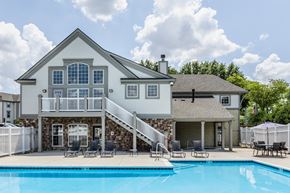 Indianapolis apartment for rent - Swimming pool  surrounded by chairs and a white fence, in front of a clubhouse.