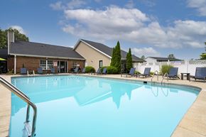Reynoldsburg apartment for rent - A large swimming pool in front of a building with a blue sky and clouds in the background.