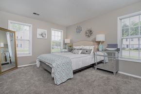 Reynoldsburg apartment for rent - A bedroom with a large bed and a mirror on the wall.