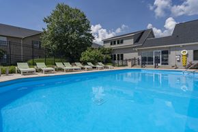 Canal Winchester apartment for rent - A large blue swimming pool with lounge chairs and a building in the background.