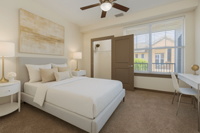 Miamisburg apartment for rent - A bedroom with a large bed, a ceiling fan, and a painting on the wall.