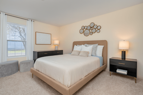 Hilliard apartment for rent - A bedroom with a large bed, two lamps, and a picture on the wall.