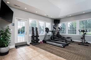 Delaware townhouse for rent - The fitness center at Carson Farms in Delaware, OH, equipped with cardio machines, strength-training equipment, and bright natural lighting.