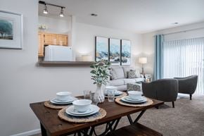 Pataskala apartment for rent - A dining table set with plates and glasses is in the foreground of a well-lit dining room.
