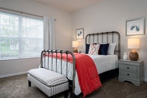 Pataskala apartment for rent - A bedroom with a large bed and a smaller bed with a red blanket.