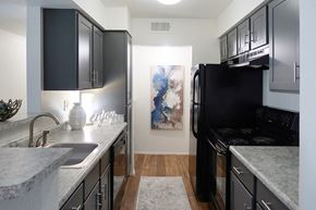 Florence apartment for rent - Modern kitchen with black appliances, granite countertops, sleek cabinetry, and wood-style flooring in a two-bedroom apartment at The Boulevard in Florence, KY