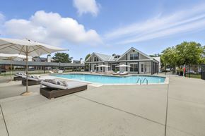 Fishers apartment for rent - A large outdoor swimming pool with sun loungers and umbrellas.