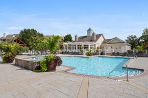 Lexington apartment for rent - A resort-style swimming pool surrounded by chairs and lush greenery.