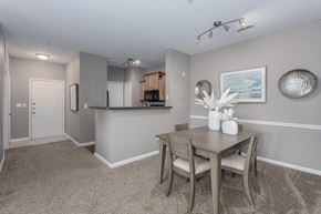 Florence apartment for rent - A dining area at Trellises with a table surrounded by four chairs on carpeted floors, next to a kitchen.