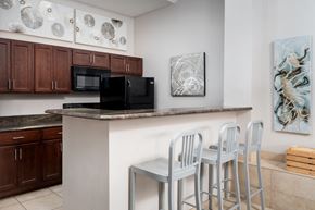 Florence townhouse for rent - A kitchen with three bar stools, black appliances, and wooden cabinets in Florence, KY.